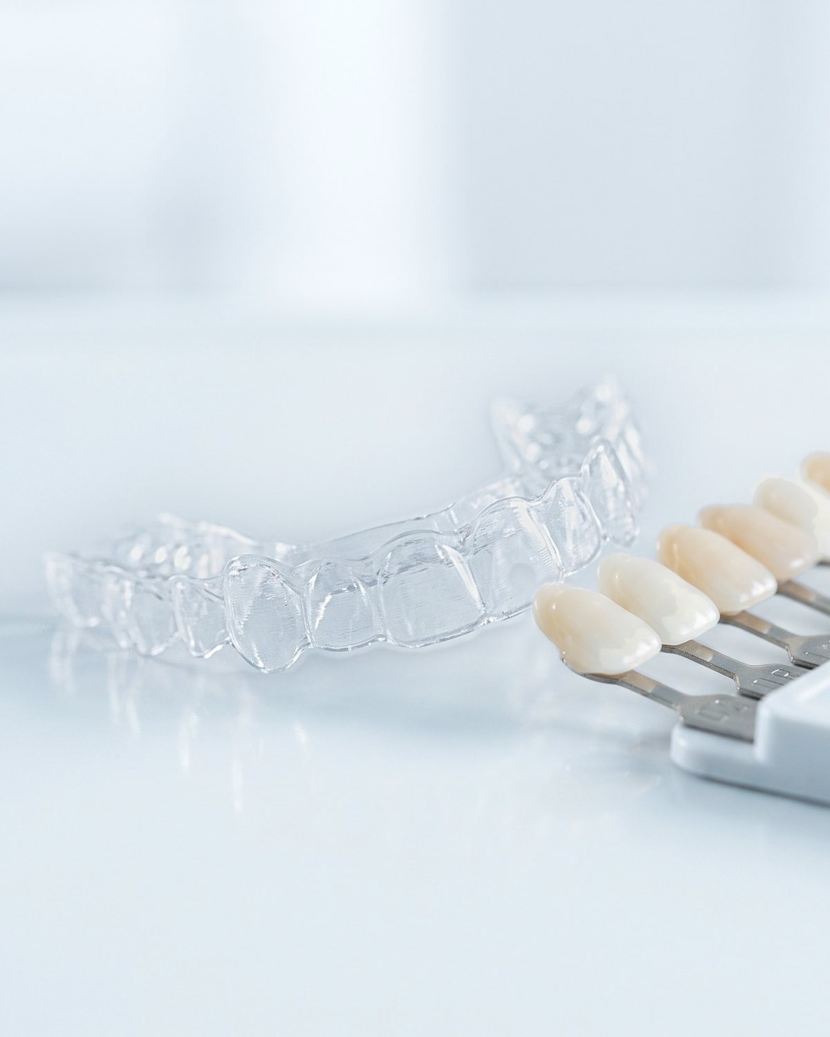 A clear custom whitening tray beside a porcelain shade guide.